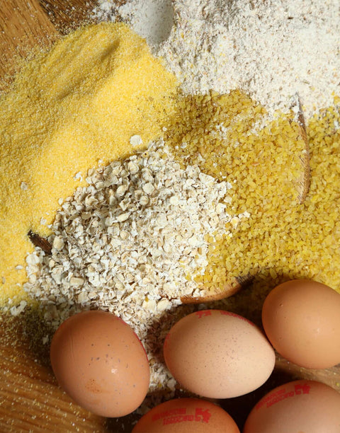 Assorted grains, oats, and brown eggs displayed on a wooden surface, highlighting natural ingredients for healthy recipes.